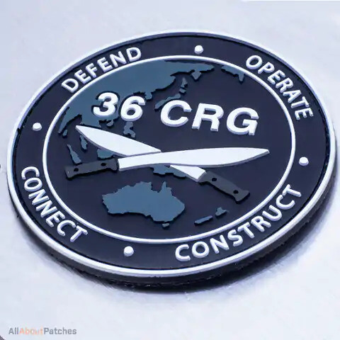 Round navy PVC patch with crossed knives over a map of Asia and Australia, on brushed metal